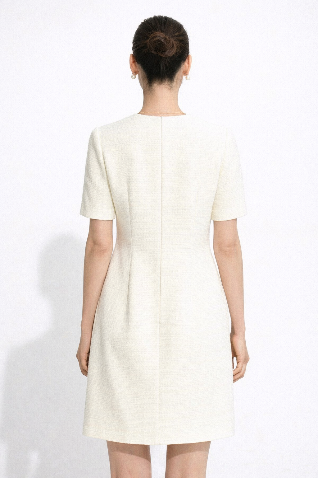 Woman wearing a white dress against a white background