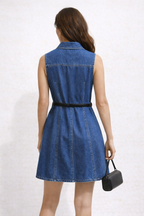 Woman wearing a blue denim dress with a black belt on a white background MARGAUX DENIM DESS ON MODEL WITH HANDBAG