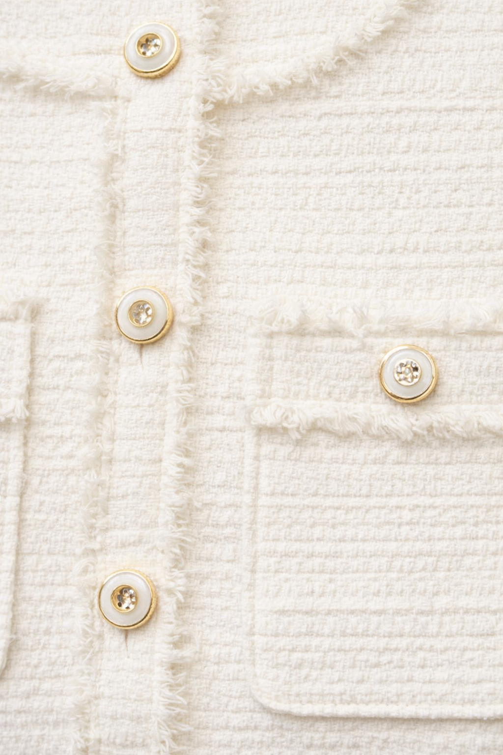 Close-up of a textured white fabric dress with gold buttons