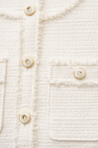 Close-up of a textured white fabric dress with gold buttons