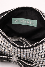 Close-up of a sparkling handbag with 'Wisteria' brand label on black interior. rhinestone bag