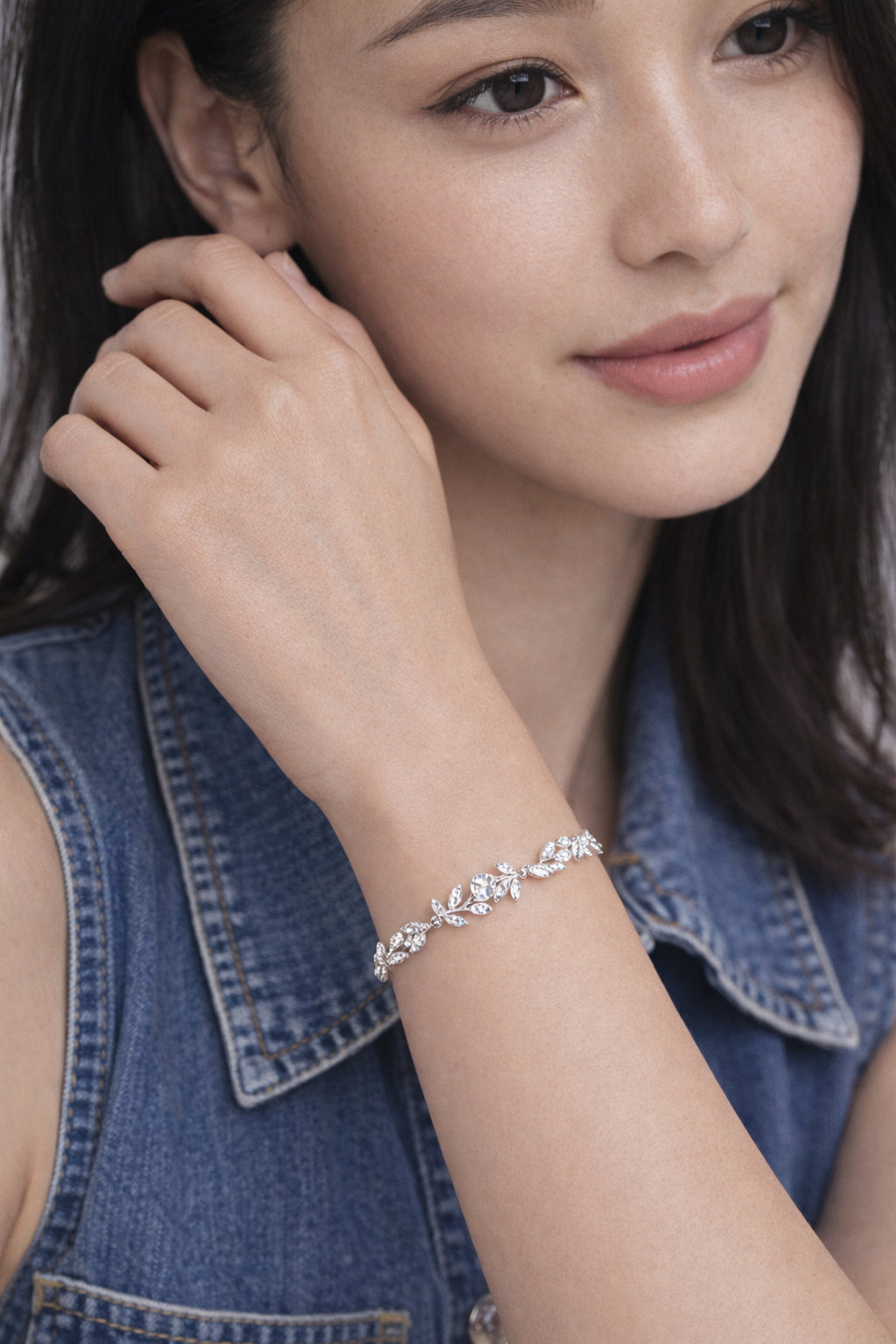 Woman model asian wearing a silver bracelet on her wrist, with a close-up of the jewelry.